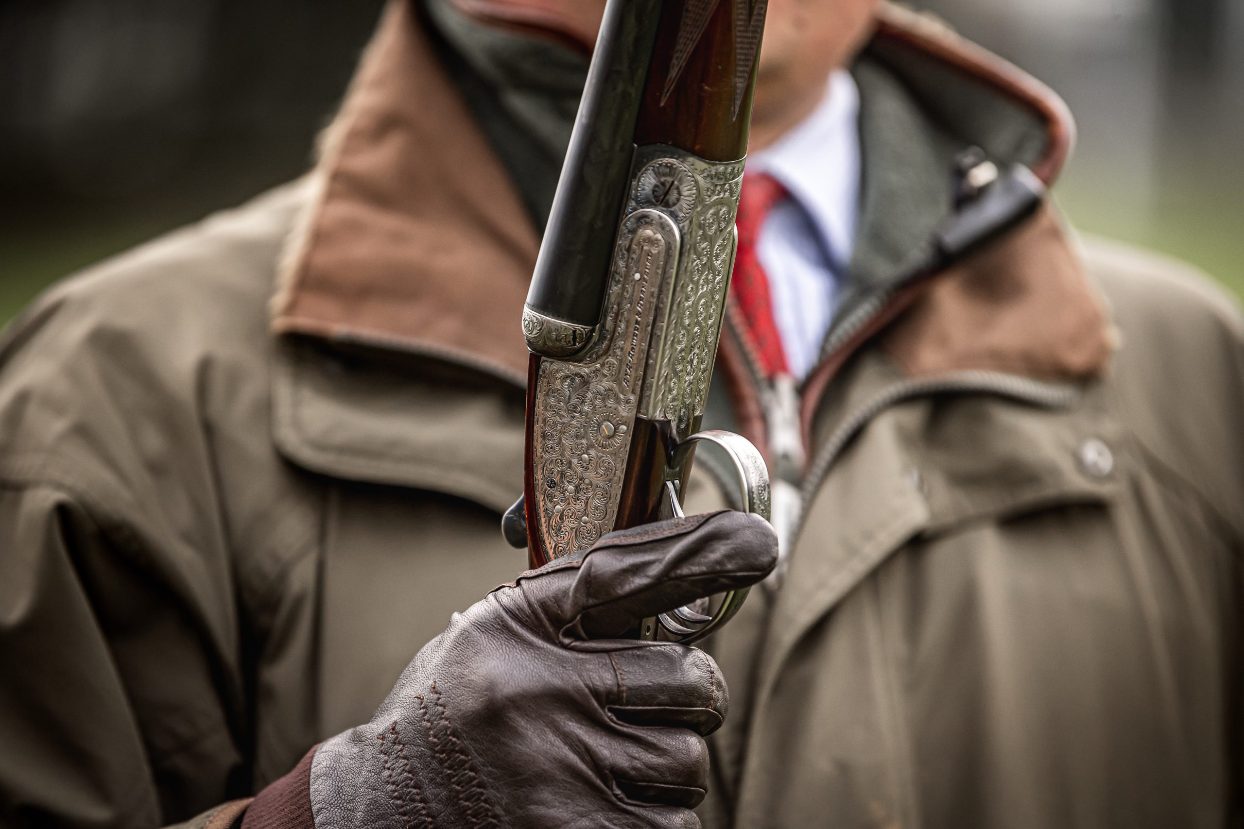 Man with a closed side by side shotgun waiting on the shooting line