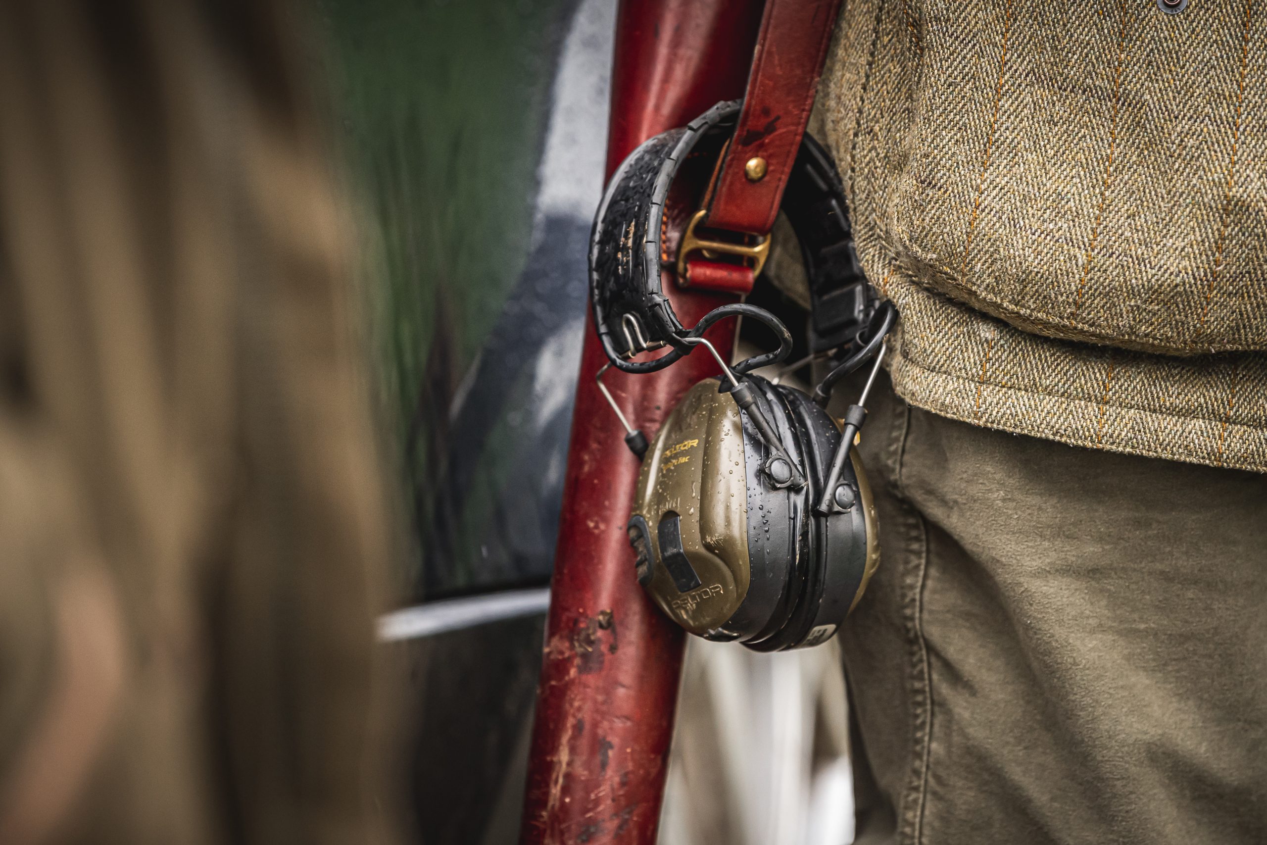 A gun slip over the shoulder of a gun with his ear defenders around the strap