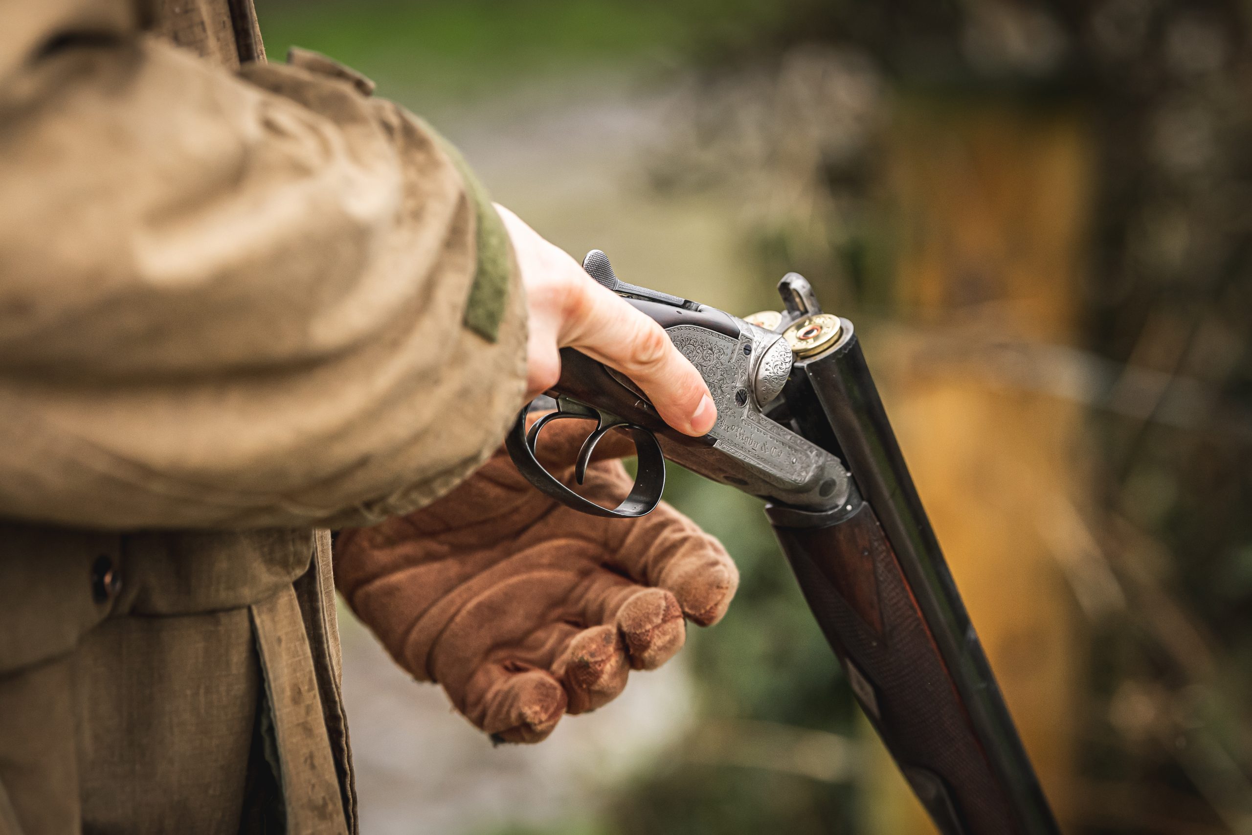 A man holding an open shotgun with cartridges in the chamber