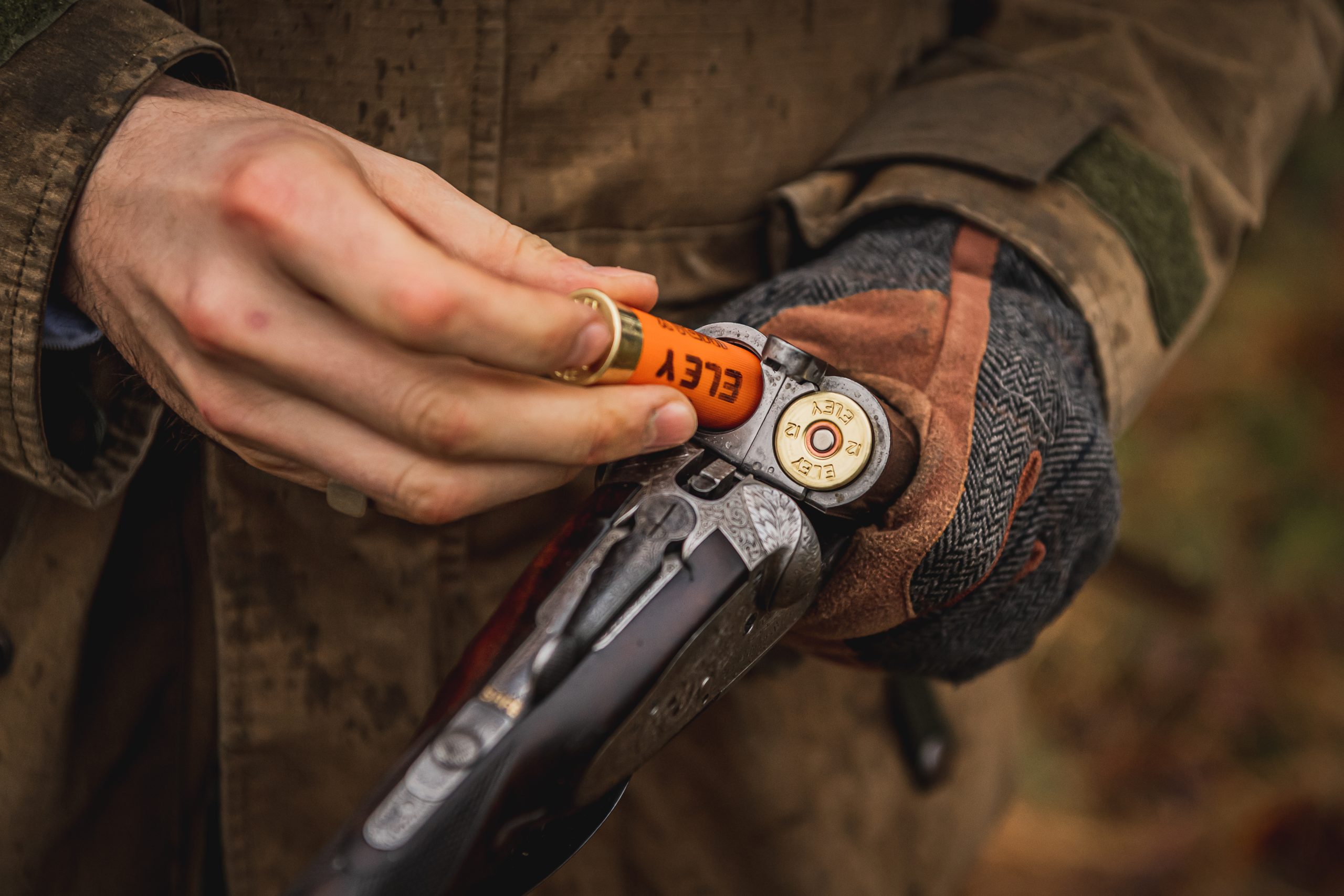 Man loading game cartridges into a side by side shotgun