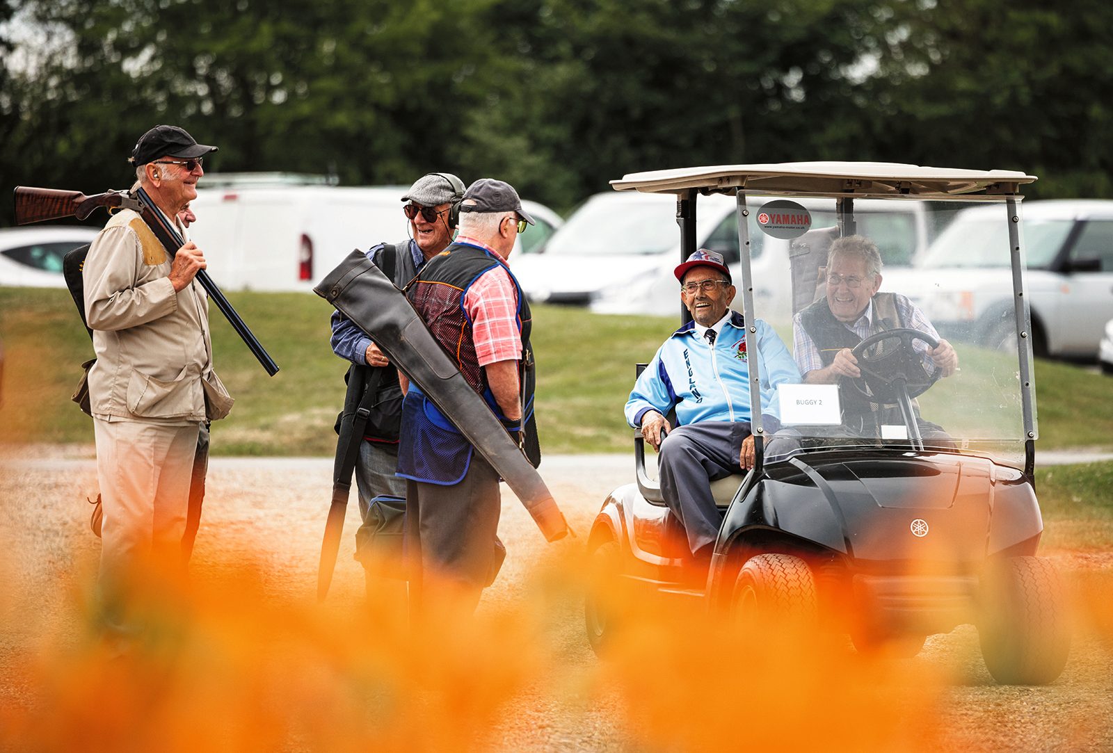 Group of clay shooters chatting beside a buggy at High Lodge shooting ground in Suffolk