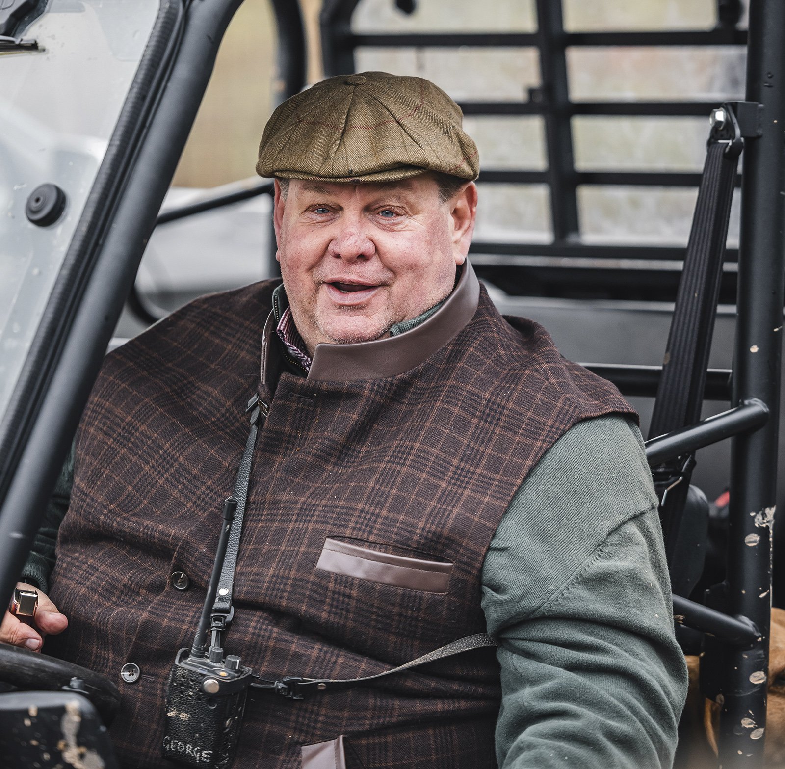 George Digweed MBE smiling in the field, seated in a shooting vehicle