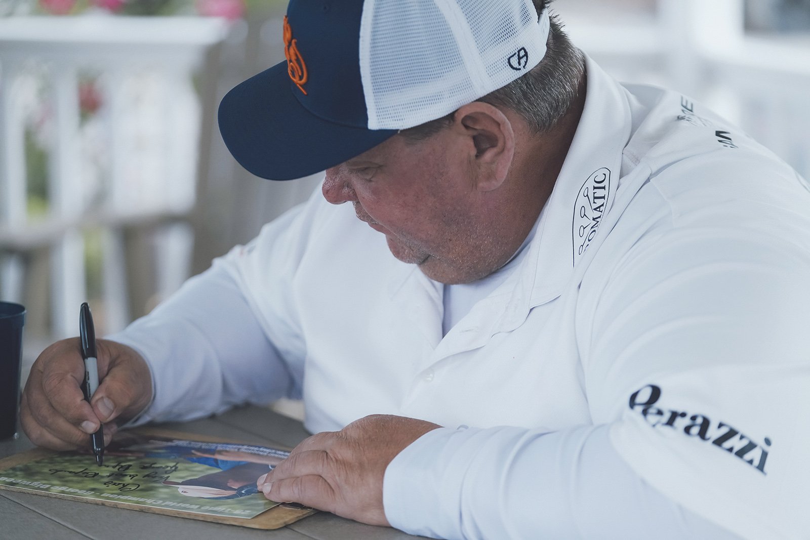 George Digweed signing autographs at a shooting event, wearing a Perazzi shirt