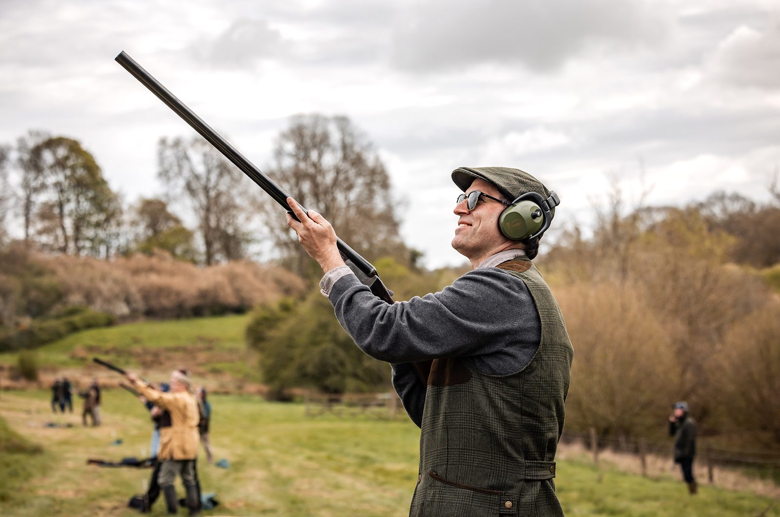 A Gun in tweed mounts an over-and-under shotgun on a simulated game day at Great Tew Estate