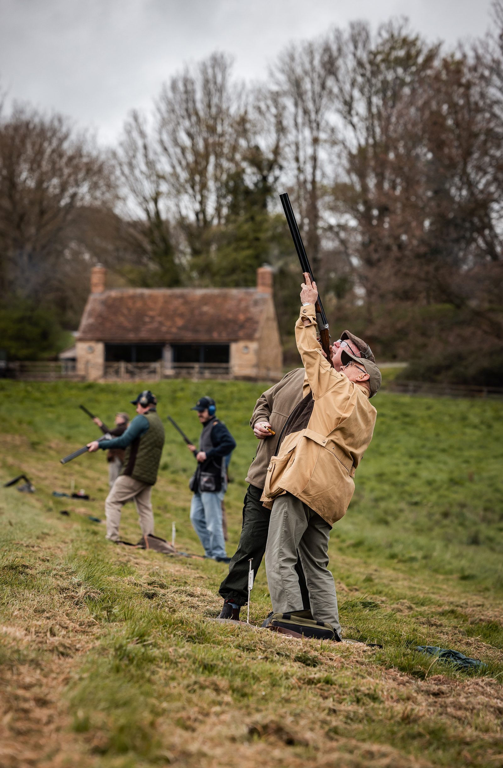 A line of Guns shooting clays beside a Cotswold stone cottage at Great Tew Estate