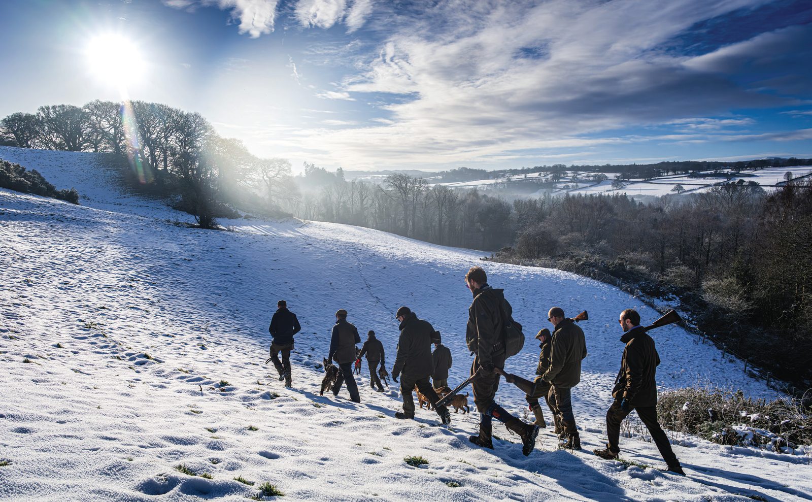 A line of guns walking across a snow-covered hillside on a driven shoot day