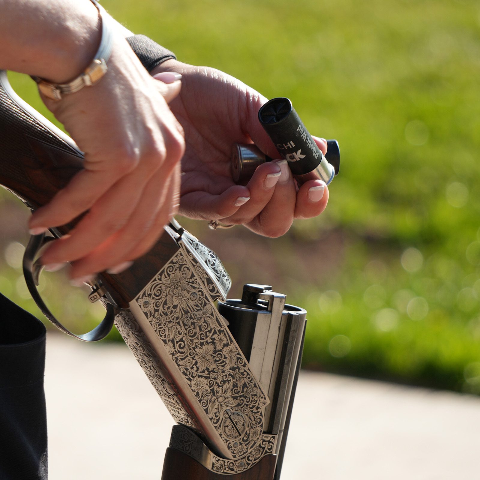 A Fiocchi FBLACK cartridge being loaded into an engraved over-and-under shotgun