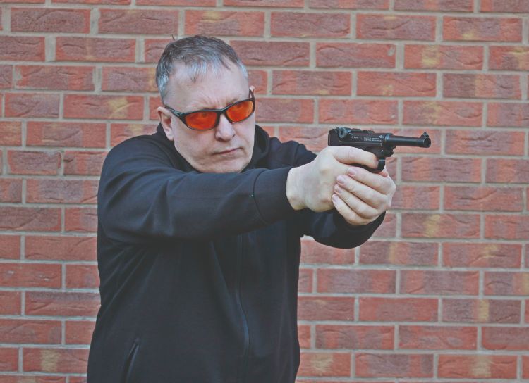 A man shooting a World War II pistol